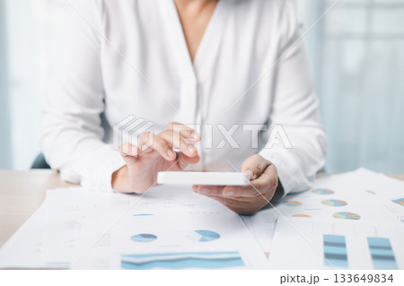 Close up of businesswoman using calculator for financial analysis and accounting on office desk with charts and reports. Concept of business planning, budget calculation and investment strategy. Close up of businesswoman using calculator for financial analysis and accounting on office desk with charts and reports. Concept of business planning, budget calculation and investment strategy. 133649834
