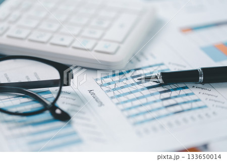 Close up of financial report with pen, calculator and eyeglasses on office desk. Concept of accounting, data analysis, audit, financial planning, transparency, accuracy and business strategy. Close up of financial report with pen, calculator and eyeglasses on office desk. Concept of accounting, data analysis, audit, financial planning, transparency, accuracy and business strategy. 133650014