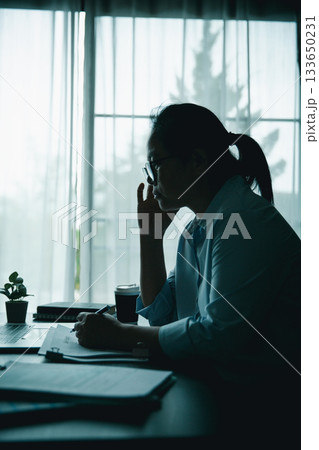 Stressed businesswoman working late at home office, feeling exhausted while reviewing financial documents on laptop. Concept of work stress, burnout, deadline, and overwork. Stressed businesswoman working late at home office, feeling exhausted while reviewing financial documents on laptop. Concept of work stress, burnout, deadline, and overwork. 133650231