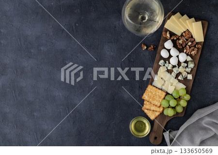 Gourmet cheese and wine pairing with crackers, grapes, and nuts on rustic board Gourmet cheese and wine pairing with crackers, grapes, and nuts on rustic board 133650569