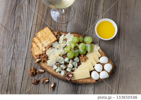 Elegant cheese and wine pairing with grapes, crackers, and walnuts on rustic wood Elegant cheese and wine pairing with grapes, crackers, and walnuts on rustic wood 133650586