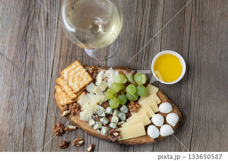 Elegant cheese and wine pairing with grapes, crackers, and walnuts on rustic wood Elegant cheese and wine pairing with grapes, crackers, and walnuts on rustic wood 133650587