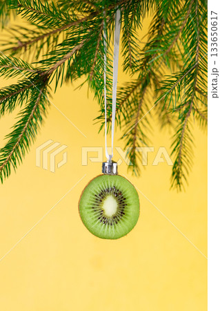 Creative christmas ornament: kiwi slice hanging on pine branch for unique holiday decor 133650617