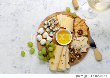 Gourmet cheese platter with grapes, nuts, and honey on rustic wooden board Gourmet cheese platter with grapes, nuts, and honey on rustic wooden board 133650634