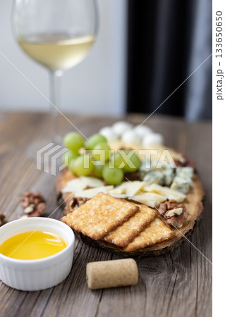 Elegant wine and cheese board with grapes and nuts on rustic wooden table Elegant wine and cheese board with grapes and nuts on rustic wooden table 133650650