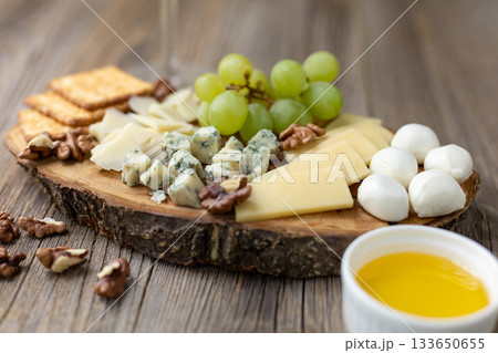 Gourmet cheese board with grapes and crackers on rustic wood background Gourmet cheese board with grapes and crackers on rustic wood background 133650655
