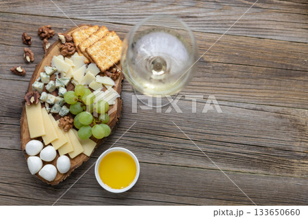 Elegant cheese and wine pairing with grapes, crackers, and walnuts on rustic wood 133650660