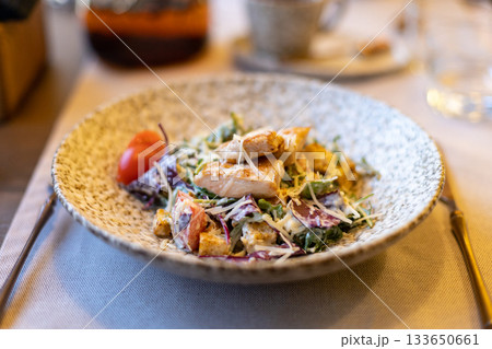 Fresh caesar salad with grilled chicken and cherry tomatoes in rustic ceramic bowl 133650661