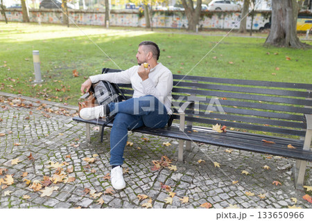 Man enjoying snack in park during autumn season 133650966