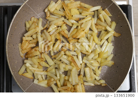 Potatoes cut into slices are deliciously fried in a frying pan. Potatoes cut into slices are deliciously fried in a frying pan. 133651900