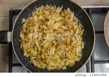 Sliced potatoes with onions are deliciously fried in a frying pan. Sliced potatoes with onions are deliciously fried in a frying pan. 133651908