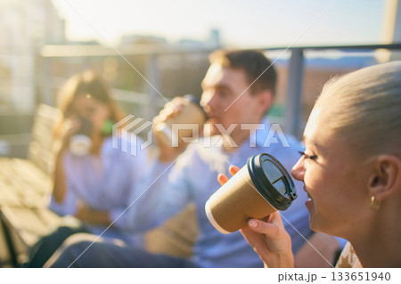 Group of coworkers drinking takeaway coffee together on sunny outdoor break Group of coworkers drinking takeaway coffee together on sunny outdoor break 133651940