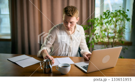 Man working with laptop and coffee cup on large office desk 133651955