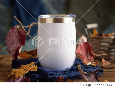 White blank Stainless Steel tumbler on wood near autumn dried leaves closeup, mockup in red and blue 133652353