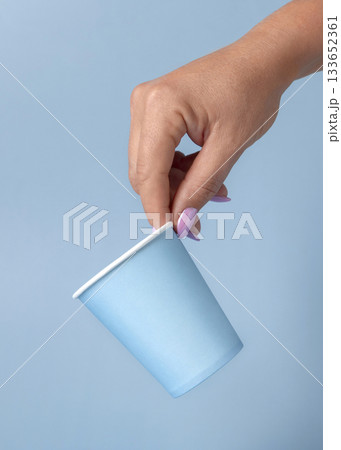 Female hand with disposable light blue paper cup closeup, mockup, copy space. Single-use cup 133652361