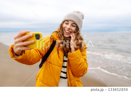 Portrait of a happy woman with a phone on the seashore. Adventure concept, vacation. 133652859