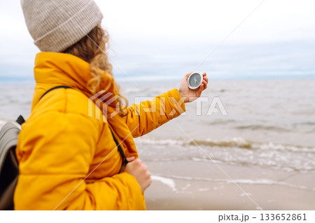 Woman traveler looking for directions with a compass on beach. Active lifestyle. Adventure concept. Woman traveler looking for directions with a compass on beach. Active lifestyle. Adventure concept. 133652861