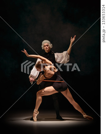 Dancer leaning forward like bowed instrument forming musical movement with violin 133653314