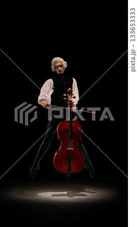 Male musician jumping with cello in dramatic airborne classical performance. 133653333