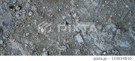 Close-up of a gray-black lava texture on the ground. Porous, cracked, and stony, perfect as a stock texture or photo background. Impression of molten rock. 133654010