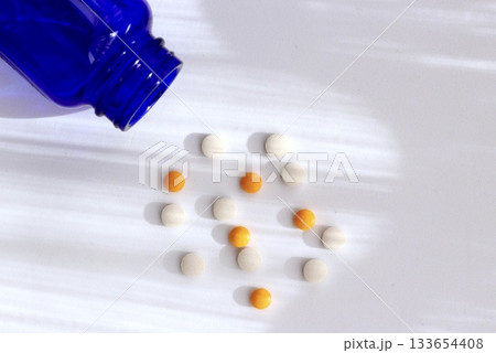 白背景に広がる錠剤と青色ボトルのヘルスケアイメージ 133654408