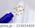 白背景に広がる錠剤と青色ボトルのヘルスケアイメージ 133654409