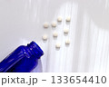 白背景に広がる錠剤と青色ボトルのヘルスケアイメージ 133654410