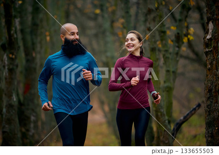 Smiling runners enjoying relaxed pace on forest trail Smiling runners enjoying relaxed pace on forest trail 133655503