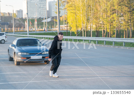 Caucasian man pulling a car with a rope.  133655540