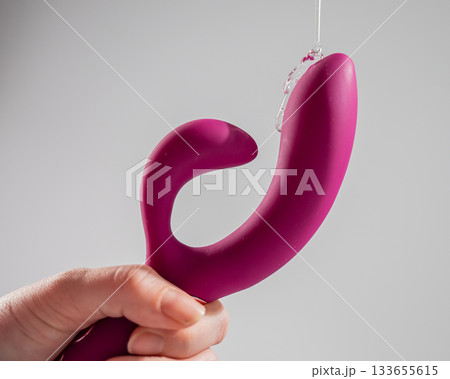 Lube pouring on pink dildo on white background.  133655615