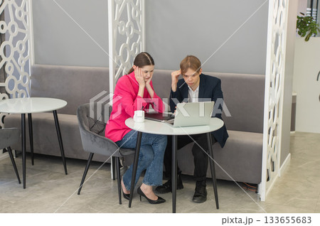 Colleagues are sitting at a laptop and discussing work. Colleagues are sitting at a laptop and discussing work. 133655683