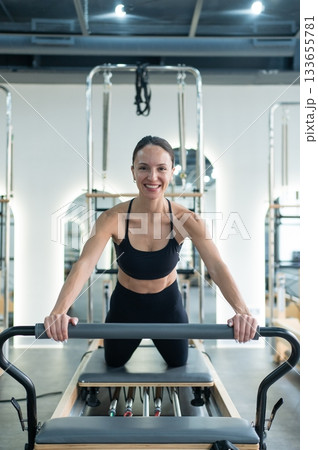 Caucasian woman doing exercises on reformer machine.  133655781