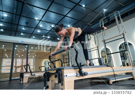 Caucasian woman doing exercises on reformer machine.  133655782