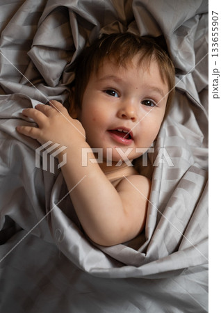 Top view of cute caucasian toddler lying in bed. Top view of cute caucasian toddler lying in bed. 133655907