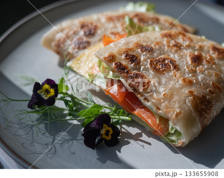 A flatbread stuffed with fish and cheese served in a cafe. Quesadilla. A flatbread stuffed with fish and cheese served in a cafe. Quesadilla. 133655908