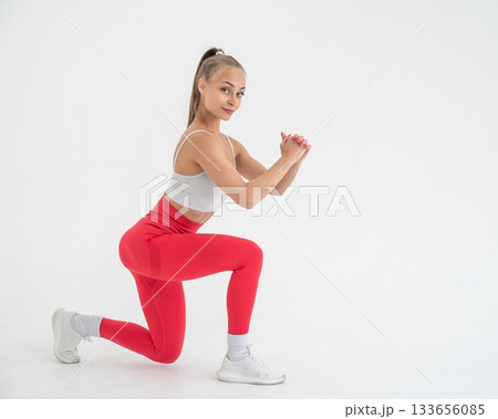 Young woman doing lunges on white cyclorama background. Vertical video.  133656085