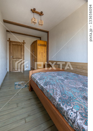 Small Cozy Bedroom Interior with Wooden Furniture and Patterned Bedspread Small Cozy Bedroom Interior with Wooden Furniture and Patterned Bedspread 133656094