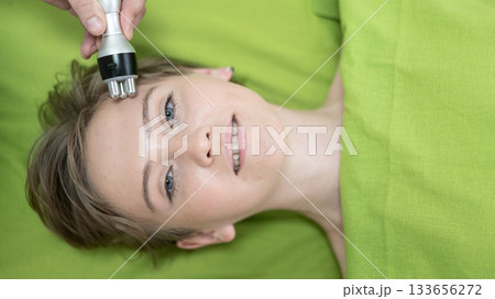 Top view of Caucasian woman undergoing radio wave RF lifting procedure in beauty salon. Top view of Caucasian woman undergoing radio wave RF lifting procedure in beauty salon. 133656272