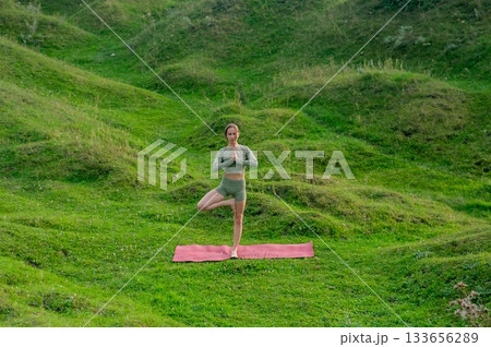 Caucasian woman doing yoga outdoors. Tree pose.  133656289