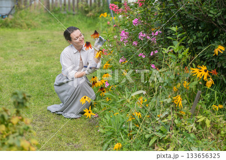Caucasian woman tending her garden. Caucasian woman tending her garden. 133656325