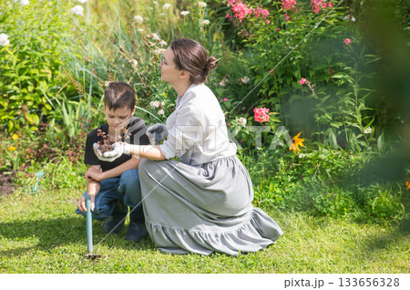 Caucasian woman tending her garden with her son.  133656328