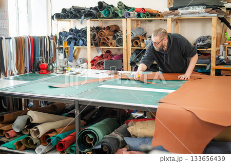Caucasian bearded man working as a tanner in a workshop.  133656439