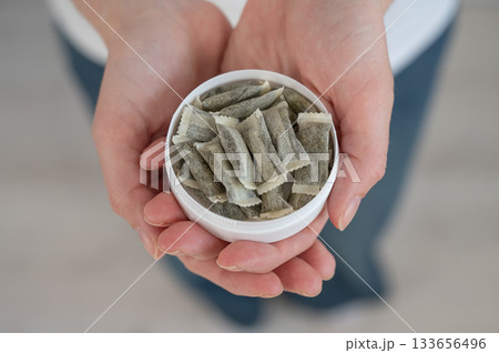 A woman holds a jar of chewing tobacco.  133656496