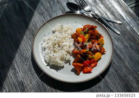 Pork in sweet and sour sauce with boiled rice on a plate. Pork in sweet and sour sauce with boiled rice on a plate. 133656525