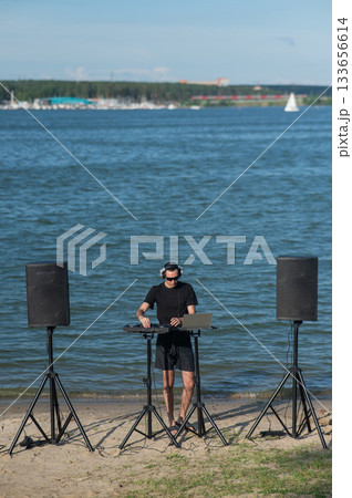 Male DJ playing music on the beach. Male DJ playing music on the beach. 133656614