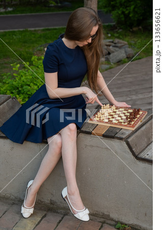Caucasian woman playing chess outdoors. Caucasian woman playing chess outdoors. 133656621