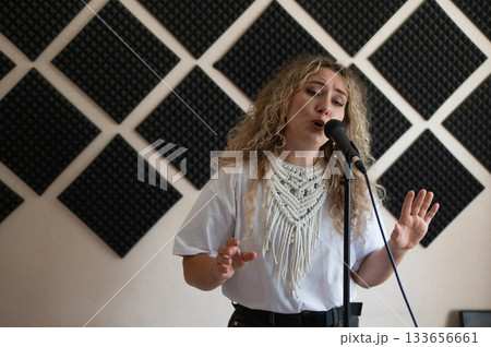 Caucasian woman singing into microphone in music studio. Caucasian woman singing into microphone in music studio. 133656661