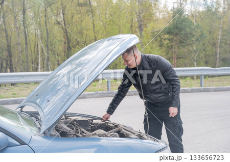 Caucasian man looking under the hood of his car. Caucasian man looking under the hood of his car. 133656723