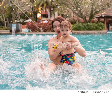 Caucasian woman holds her son while swimming in a pool on vacation. Mom teaches little boy to swim. Caucasian woman holds her son while swimming in a pool on vacation. Mom teaches little boy to swim. 133656752