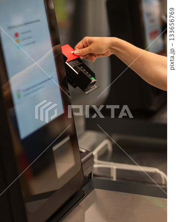 Woman paying with credit card at self-checkout.  133656769
